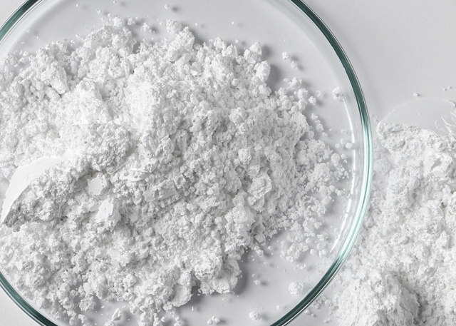 Glass bowl filled with sulfate powder on white background with powder scattered nearby illustrating sulfate-free benefits