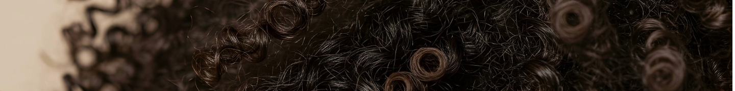 Close-up of tightly coiled hair texture with fingers gently separating curls