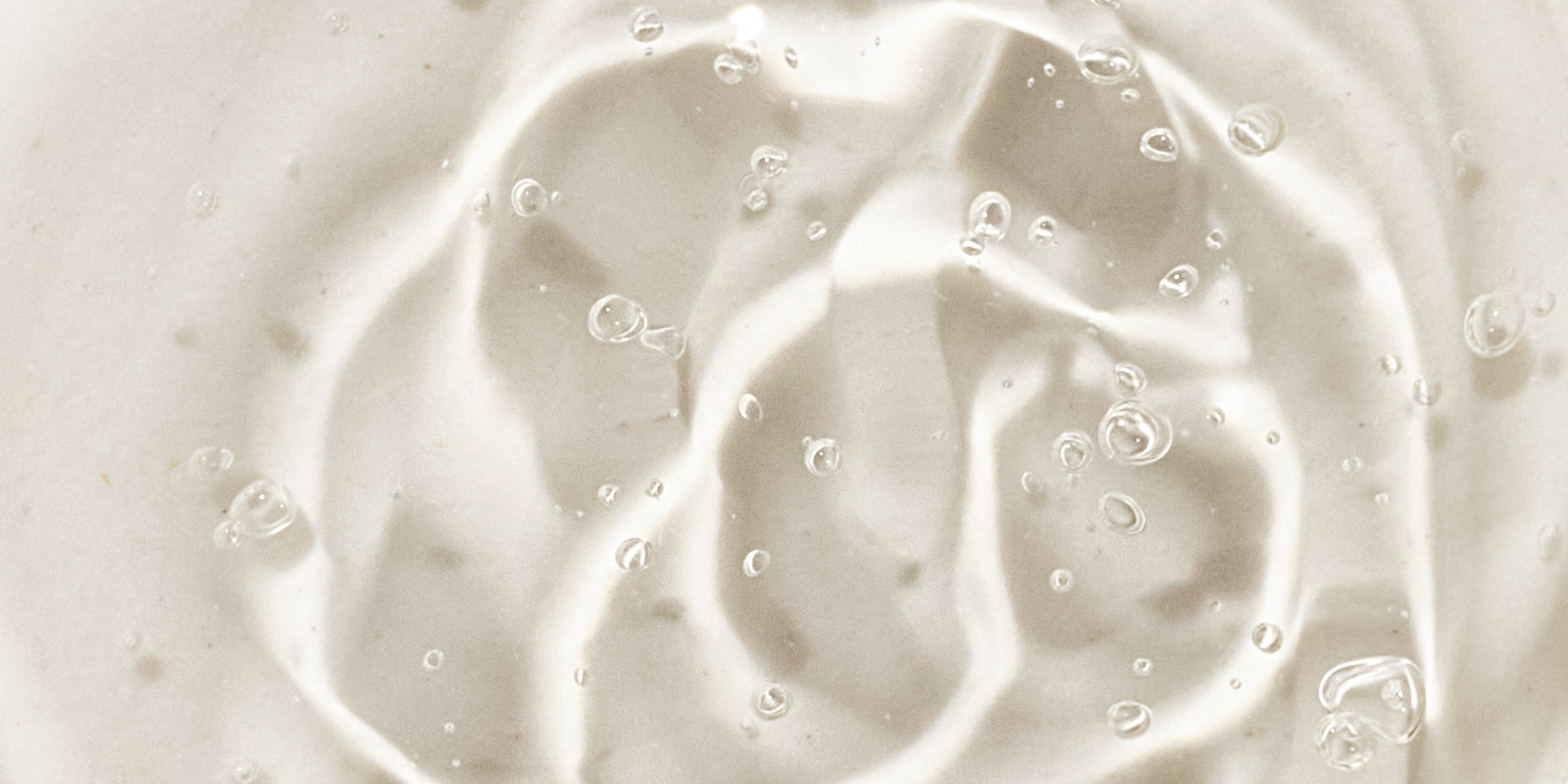 A macro shot of translucent hair gel, swirled gel with trapped air bubbles on a light background