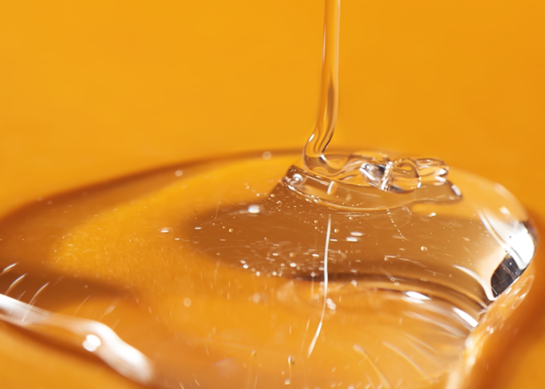 Clarifying shampoo oozes onto an orange surface.