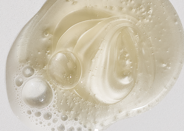 Close-up of a gentle sulfate-free shampoo's viscous, bubbly texture on a white background.
