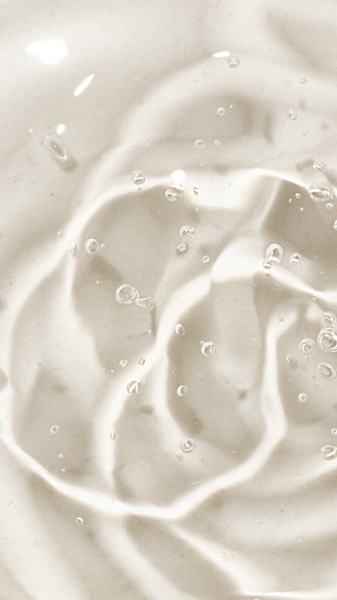A macro shot of translucent hair gel, swirled gel with trapped air bubbles on a light background