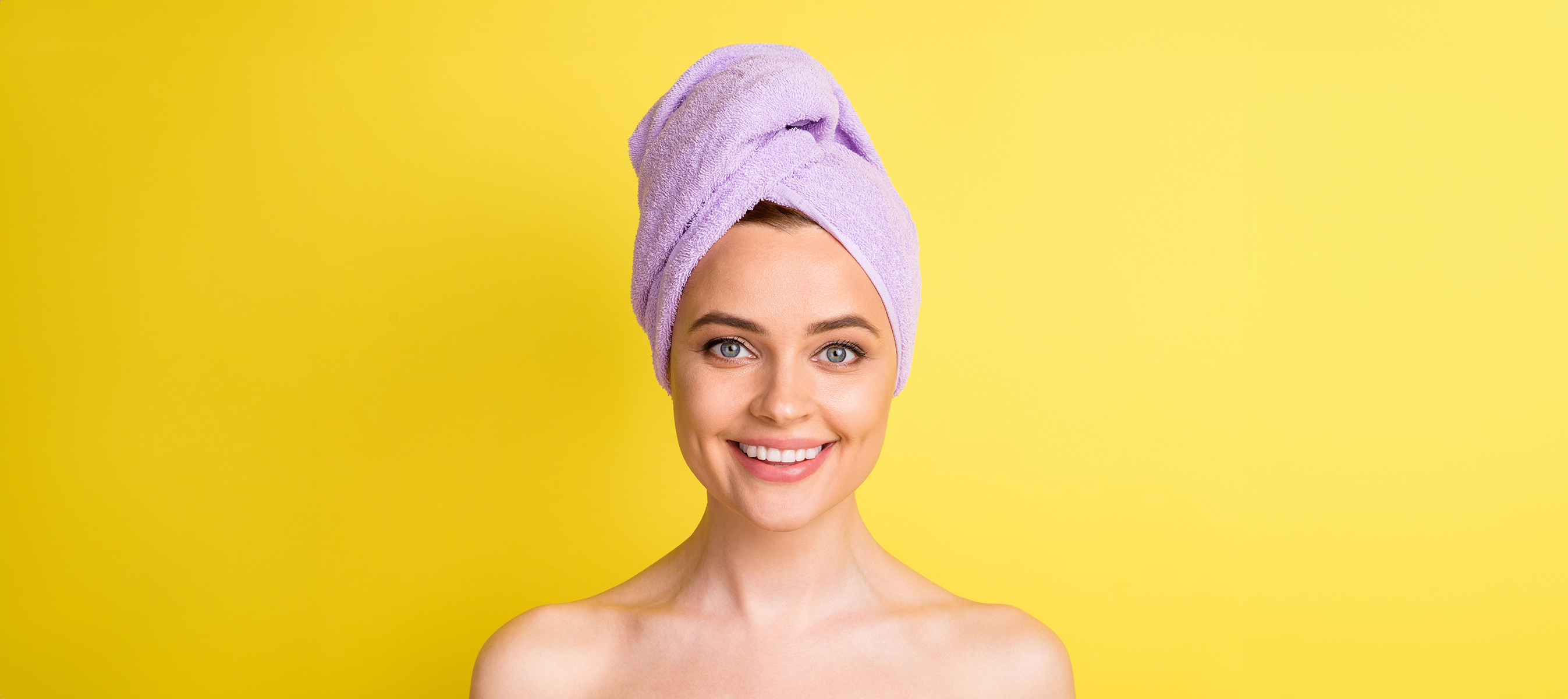 Close-up portrait of lovely cheerful girl wearing towel on head after a fresh shower, isolated over bright yellow color background